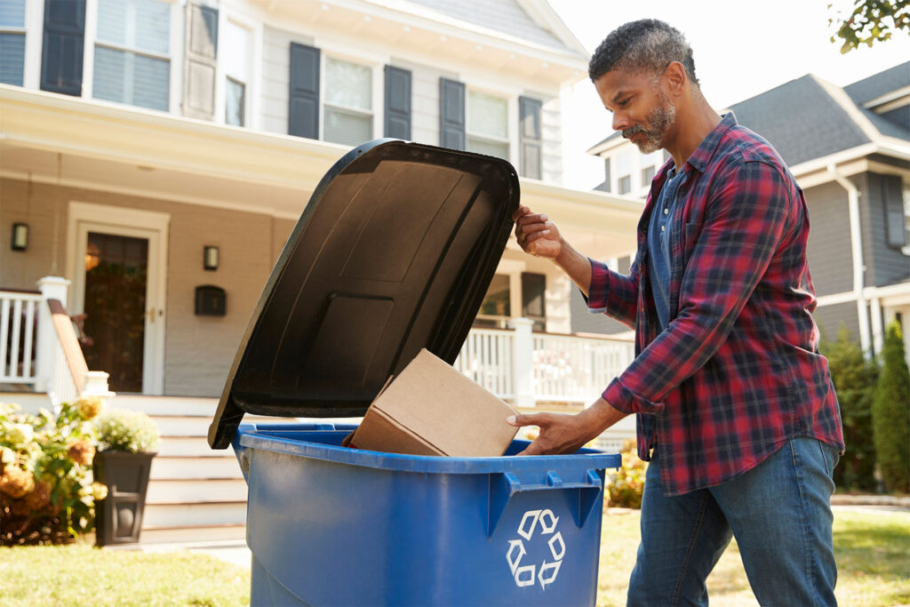 man filling recycling bin on curb