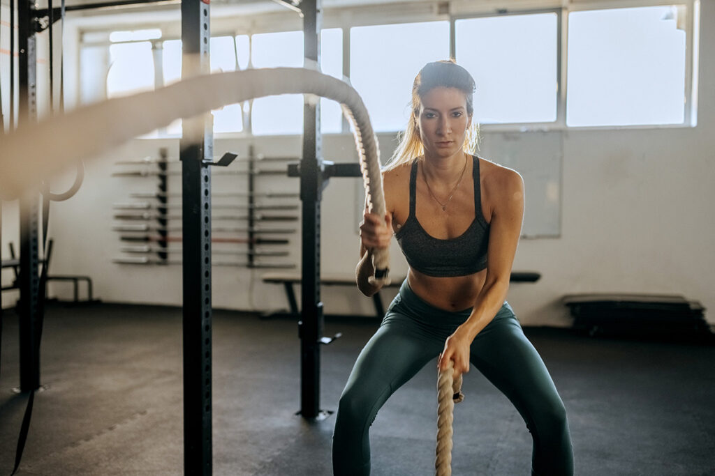 woman at crossfit gym working out with ropes
